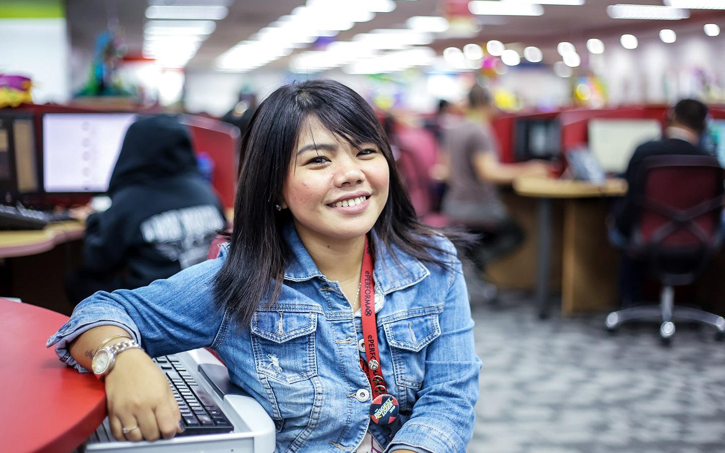 Female customer service outsourcing agent in the Philippines smiling at desk